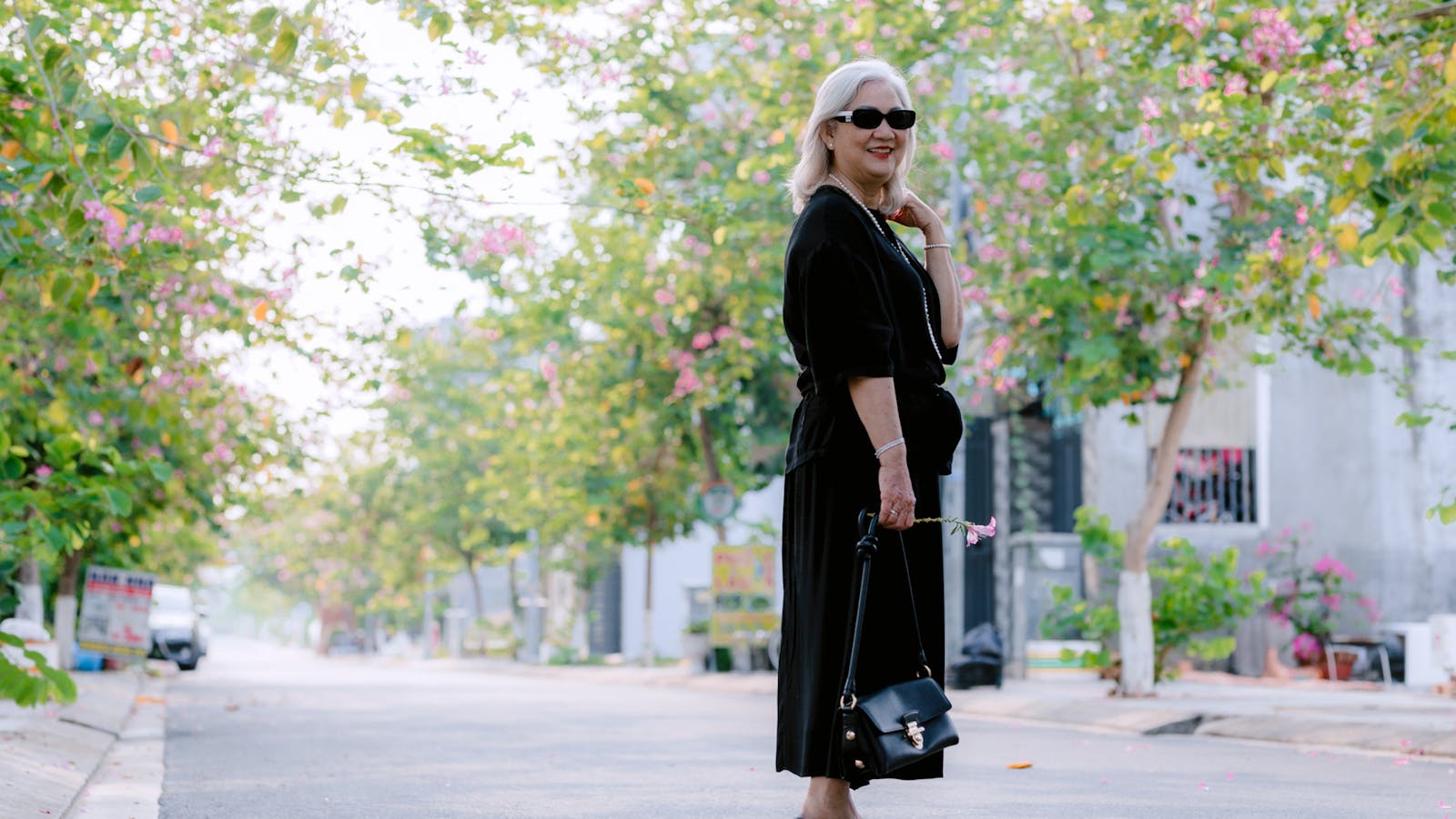 A companion and an older woman walking together through a sunlit neighbourhood